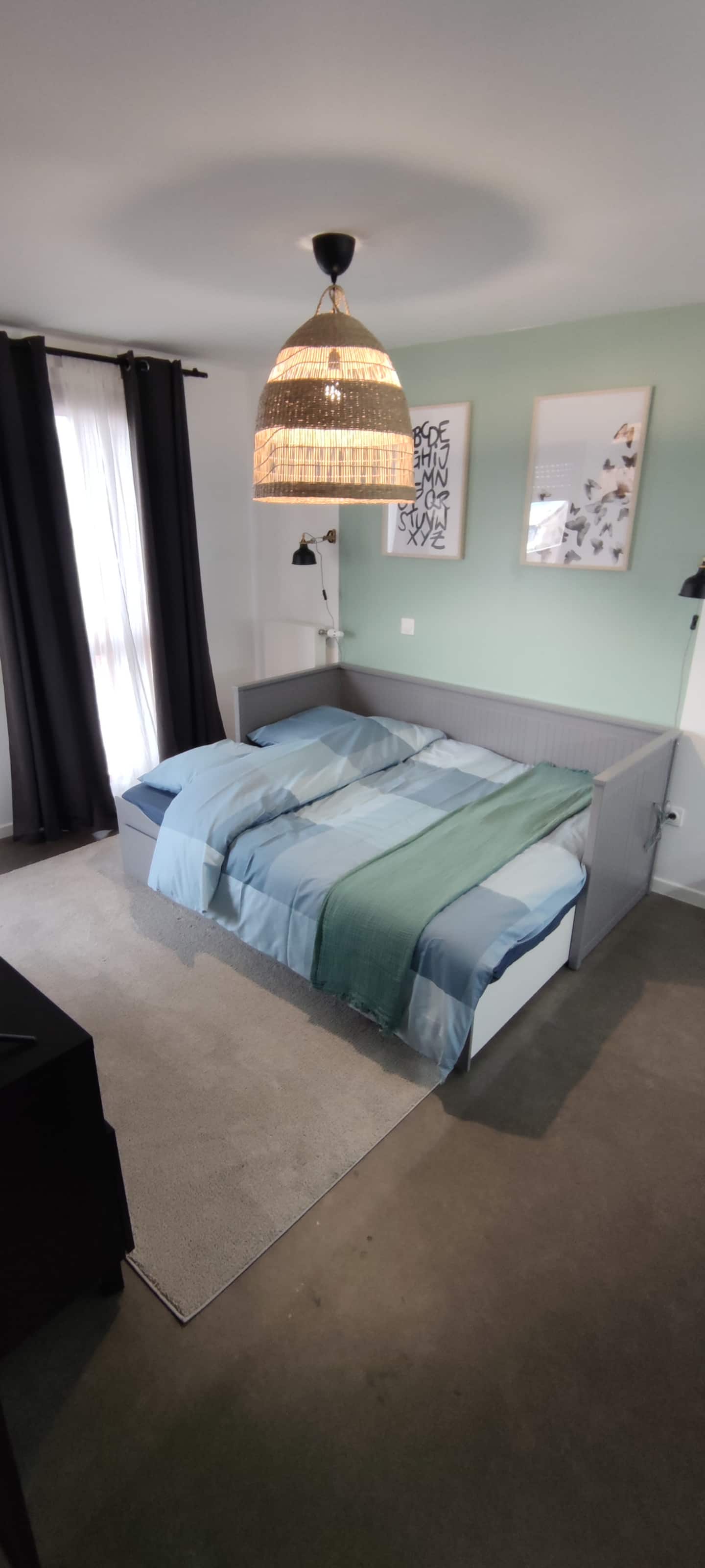 Espace nuit du studio avec canapé-lit double et mur vert d'eau